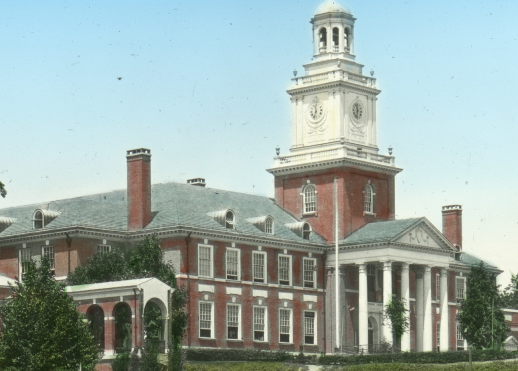 Colorized photo of Gilman Hall, showing its top two floors and columned entrance and clock tower.