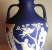 A blue vase with depictions of a Greek mythological scene painted on white.