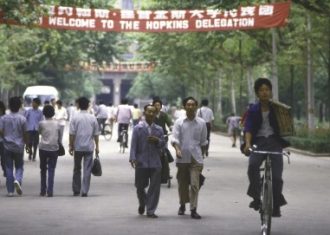 Photos of people in China walking down a street with Banners red banners overhead.