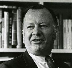 Black and white portrait photo of Chester Wickwire in front a bookcase.