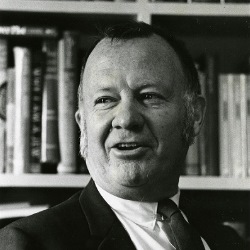 Black and white portrait photo of Chester Wickwire in front a bookcase.