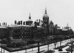 Wide shot of a brick multi-story brick building in black and white.