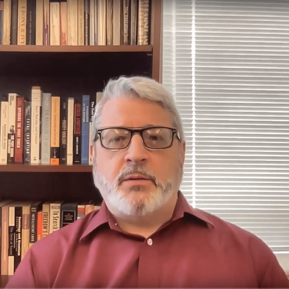 Screenshot of a fair skinned man wearing glasses talking on a zoom call.
