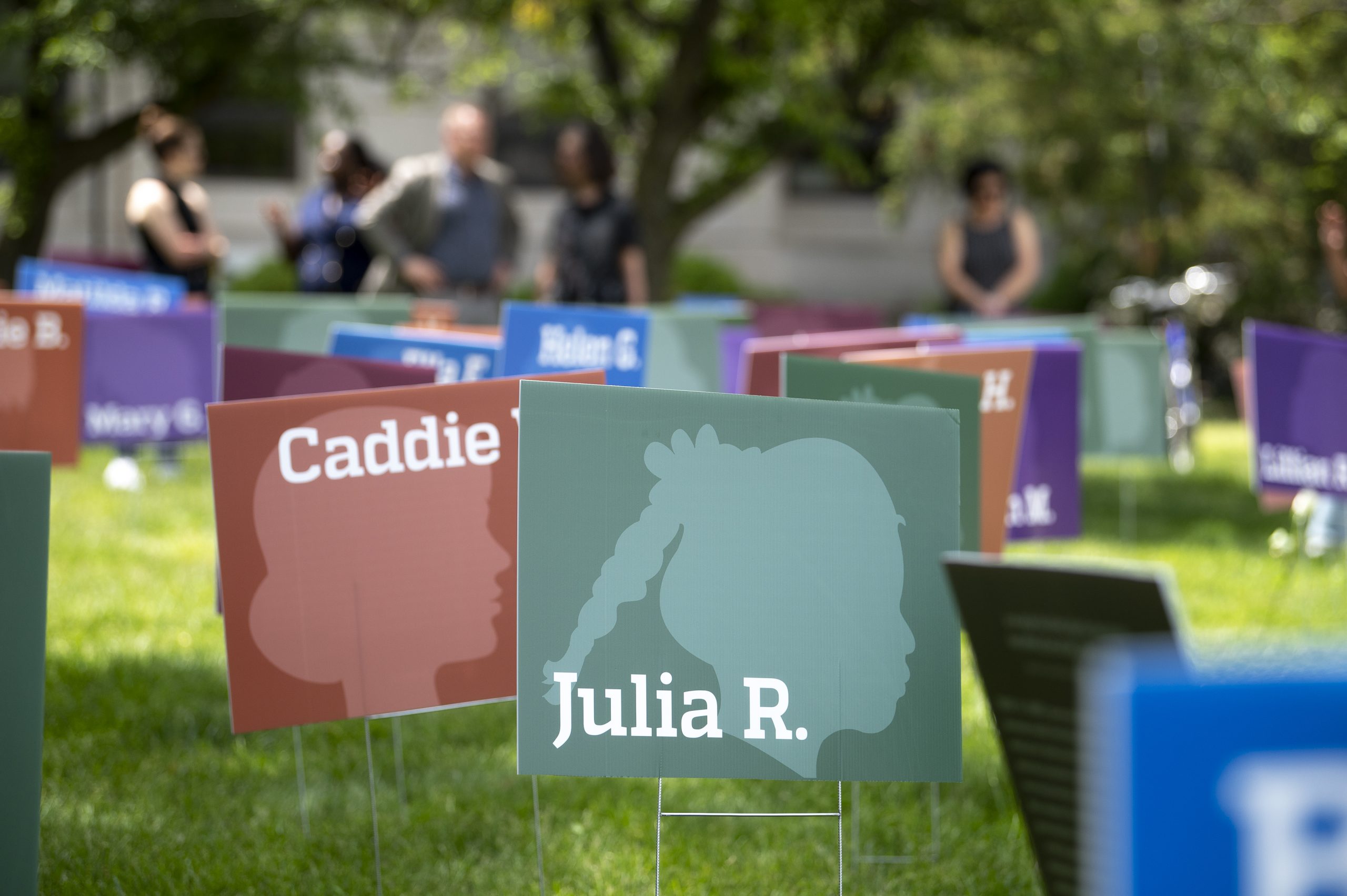 Several yard signs designed with profile silhouettes of Back girls and their names.