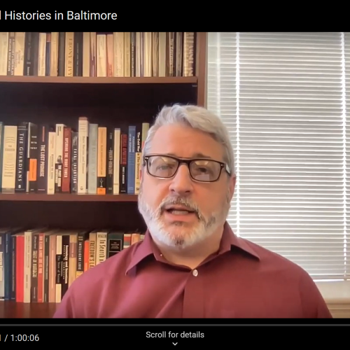 Screenshot of a fair skinned man wearing glasses talking on a zoom call.