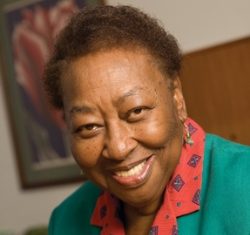 Portrait photo of a women with a small fro and wearing a blue and red blazer.