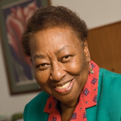 Portrait photo of a women with a small fro and wearing a blue and red blazer.